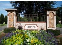 Cheval community entrance featuring a stone pillar design, wrought iron gate, and vibrant floral landscaping at 2336 Salute Blvd, Mint Hill, NC 28227