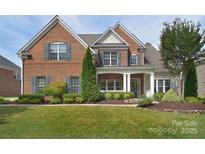 Charming brick home featuring manicured landscaping, lush green lawn, and a welcoming front porch at 2812 Julian Glen Cir, Waxhaw, NC 28173