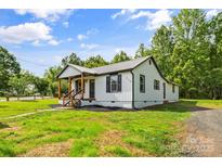 Charming exterior view of home showcasing the metal roof and manicured yard with mature trees at 320 E Pine St, Maiden, NC 28650