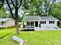Charming white ranch home featuring black trim, a cozy front porch, and a lush green lawn at 330 Willow Oak Cir, Lancaster, SC 29720