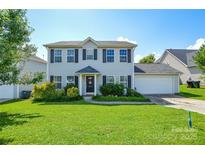 Charming two-story home with a well-manicured lawn, lush landscaping, and an attached two-car garage at 4075 Clover Nw Rd, Concord, NC 28027