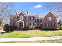 Stately brick home featuring dormer windows, mature landscaping, and a well-manicured lawn at 5004 Woodview Ln, Matthews, NC 28104