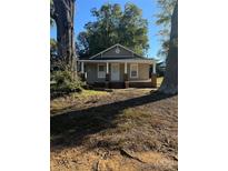 Charming one-story home featuring a welcoming front porch with brick accents and mature trees at 524 Railroad Nw Dr, Concord, NC 28025