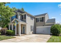 Charming two-story home featuring a welcoming front porch and attached two-car garage on a sunny day at 6107 Raisin Tree Ln, Charlotte, NC 28215