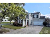 Charming two-story home with a well-manicured lawn, gray siding, and a driveway leading to an attached garage at 6107 Raisin Tree Ln, Charlotte, NC 28215