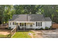 Charming one-story home with a landscaped front yard, a porch swing, and a fenced yard at 800 Woodlawn St, Belmont, NC 28012