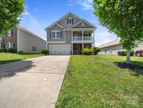 Charming two-story home features a welcoming porch, a well-manicured lawn and an attached two car garage at 10426 Kempsford Dr, Charlotte, NC 28262