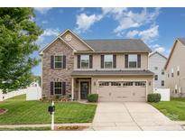 Charming two-story home with a stone and siding exterior, a well-manicured lawn, and a two-car garage at 12822 Plumleaf Dr, Charlotte, NC 28213
