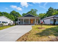 Charming gray home featuring a cozy front porch and an expansive concrete driveway at 251 Hall Nw Ave, Concord, NC 28027