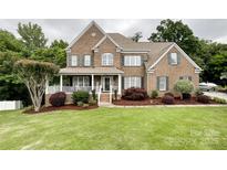 Charming two-story brick home featuring a welcoming front porch and beautifully landscaped front yard with lush green grass at 2652 Bedford Nw Pl, Concord, NC 28027