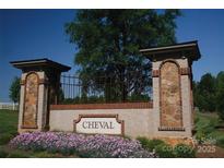 A welcoming Cheval community entrance with stone pillars, iron gate, and colorful flower beds at 3728 Piaffe Ave, Mint Hill, NC 28227