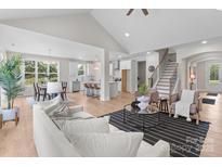 Bright open-concept living room featuring hardwood floors, modern furnishings, and a view into the kitchen and dining area at 4949 Rimer Rd # 4, Concord, NC 28025
