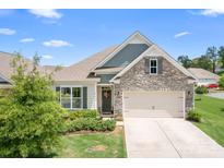 Charming home with a stone facade, manicured lawn, and a two-car garage, under a clear blue sky at 5058 Antebellum Dr, Iron Station, NC 28080