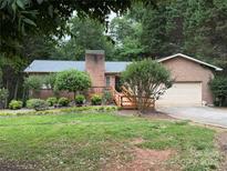 Charming brick home featuring a manicured lawn, a chimney, and a wooden deck at 5198 Wright Dr, Hickory, NC 28602