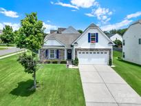 Charming two-story home featuring a manicured lawn, stone accents, and a two-car garage at 6192 Kilchurn Dr, Fort Mill, SC 29707