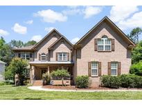 Charming brick home featuring a manicured lawn and inviting front porch at 6300 Latta Springs Cir, Huntersville, NC 28078