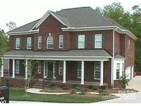 Traditional brick two-story home featuring a welcoming front porch with white columns and a well-manicured lawn at 1009 Brookline Dr, Huntersville, NC 28078