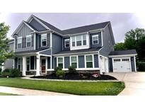 Two-story home with blue siding, white trim, attached two car garage, and a manicured front yard at 10112 Andres Duany Dr, Huntersville, NC 28078