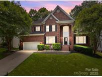 Beautiful two-story brick home with a well-manicured lawn, mature trees, and an attached two-car garage at 11909 Cupworth Ct, Huntersville, NC 28078