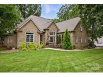 Charming brick home featuring a lush lawn, mature trees, and tasteful landscaping at 12900 Westmoreland Rd, Huntersville, NC 28078