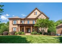 Stunning brick and stone home featuring a manicured lawn, mature landscaping and inviting covered front porch at 13056 Long Common Pkwy, Huntersville, NC 28078