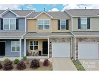 Charming townhome showcasing a one-car garage and a cozy front porch, with diverse exterior colors and stone accents at 16039 Simril Ct, Charlotte, NC 28278