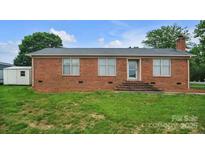 Charming single-story brick home featuring a well-maintained lawn and a detached storage shed at 1609 Mcfarland Dr, Shelby, NC 28152
