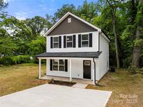 Charming two-story home featuring a classic white facade, black shutters and a welcoming covered front porch at 208 N Correll St, Landis, NC 28025