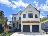 Charming two-story home with a white brick facade, dark trim, and a two-car garage at 2414 E 7Th St, Charlotte, NC 28204