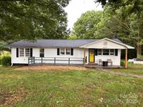 Charming single story home featuring a cozy porch, black shutters, and a bright yellow door at 2903 Price Rushing Rd, Monroe, NC 28110
