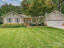 Charming single-story home with well-manicured lawn, attached garage, and mature landscaping at 2911 Butter Churn Ln, Matthews, NC 28105