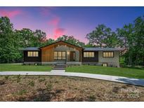 Stunning single-story home with a modern design and inviting walkway, surrounded by lush greenery and mature trees at 5033 Waxhaw Indian Trail Rd, Matthews, NC 28104