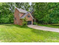A charming two-story brick home sits on a lush green lot, surrounded by mature trees and features an attached two car garage at 530 Shady Oaks Dr, Stanley, NC 28164