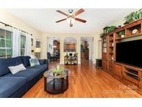 Inviting living room featuring hardwood floors, a ceiling fan, and custom built-in shelving at 530 Shady Oaks Dr, Stanley, NC 28164