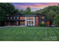 Striking modern home with unique architectural details, colorful sunset, and a well-manicured front lawn at 5925 Creola Rd, Charlotte, NC 28270