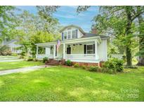 Charming home featuring a spacious front porch, lush green lawn, and mature trees offering shade at 636 N Center St, Statesville, NC 28677