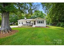 Charming single-story home featuring a well-manicured lawn, deck, and beautiful landscaping at 103 W Sunset Dr, Locust, NC 28097
