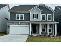 Charming two-story home featuring a stone facade, two-car garage, and inviting front porch at 1431 Hubert Graham Way, Tega Cay, SC 29708