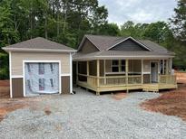 Charming single-Gathering home featuring a covered porch, neutral siding, and a detached garage in a wooded neighborhood at 1987 Robert Rufty Ln, Catawba, NC 28609