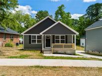 Charming newly built one-story home with gray siding, a front porch and mature trees at 212 N Correll St, Landis, NC 28025