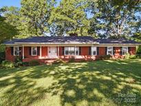 Charming brick home features a covered front porch, black shutters, and a spacious lawn at 2216 Griffith Rd, Monroe, NC 28112