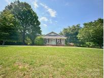 Charming home with a light-colored facade, complemented by lush greenery, set under a partly cloudy sky at 329 Highland Dr, Lincolnton, NC 28092
