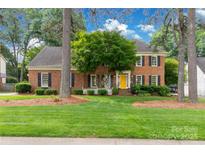 Charming brick home with black shutters, yellow front door, manicured lawn, and mature trees, creating a welcoming curb appeal at 5517 Alexa Rd, Charlotte, NC 28277