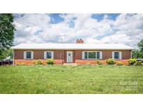 Charming brick ranch home featuring a white roof, tidy lawn, and well-maintained landscaping at 765 York Institute Rd, Hiddenite, NC 28636