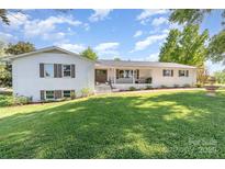 Charming white brick home featuring lush front yard and a cozy front porch at 1041 Brawley School Rd, Mooresville, NC 28117