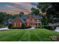 Stately brick home with manicured lawn, lush landscaping, and inviting curb appeal in a serene, wooded setting at 132 Parkside Ln, Mooresville, NC 28117