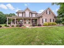 Charming brick home featuring a covered front porch and lush landscaping at 1533 Ohara Plantation Ct, Dallas, NC 28034