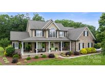 Charming brick home featuring a large front porch with decorative columns and lush landscaping at 1533 Ohara Plantation Ct, Dallas, NC 28034