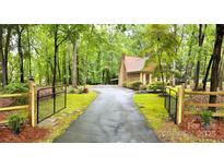 A private driveway leads to a charming house surrounded by lush greenery and mature trees at 3214 Tilley Morris Rd, Matthews, NC 28105