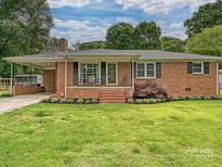 Charming single-story brick home with a well-manicured front yard, inviting porch, and convenient covered carport at 407 S Buckoak St, Stanley, NC 28164